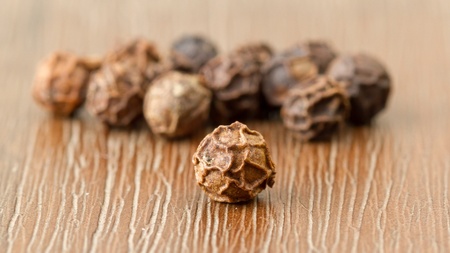 Black pepper isolated on a wooden background