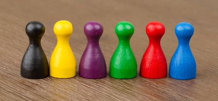 Six colored pawns isolated on a wooden backgroundの写真素材