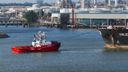 ROTTERDAM, THE NETHERLANDS - JUNE 22: Two tugboats manoeuvring an oil tanker in the dutch harbor of...