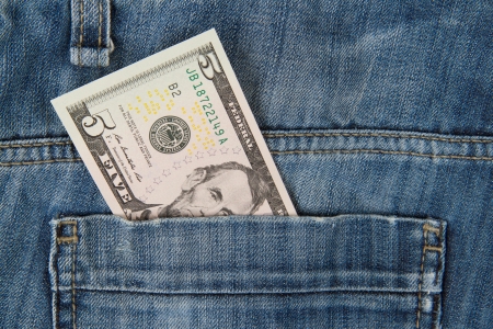 Macro shot of trendy jeans with american 5 dollar bill on its pocket
