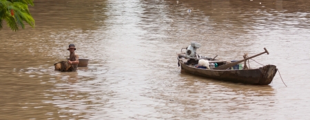 A vietnamese fisherman is searching for shells in the water in Saigonのeditorial素材
