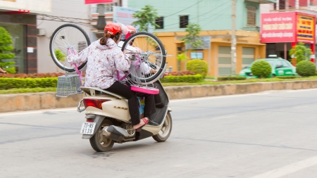 DONG HOI, VIETNAM, 7 AUGUST 2012 - Complete Vietnamese family with a bicycle on a scooter. With an estimated number of 20 million the scooter is Vietnams most important means of transportation. DONG HOI, 7 AUGUST 2012のeditorial素材