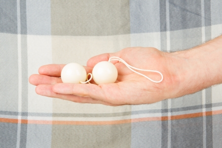 Hand holding white Intercourse balls, isolated on an old quilt