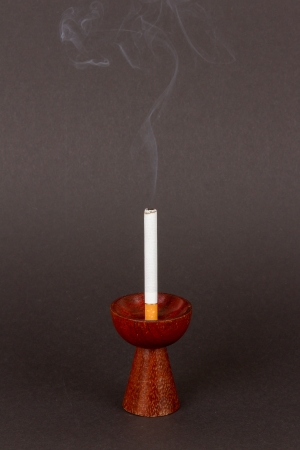 Burning cigarette in a candleholder on black backgroundの写真素材