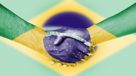 Man and woman shaking hands, arms wrapped in the flag of Brazilの写真素材