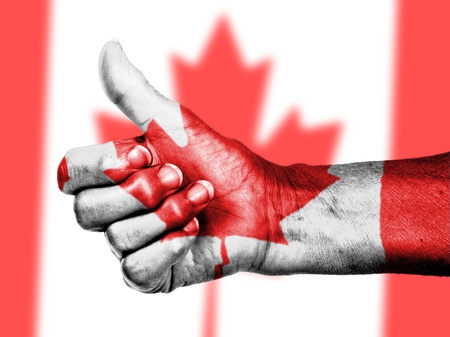 Canadian flag on thumbs up hand isolated on a flag backgroundの写真素材