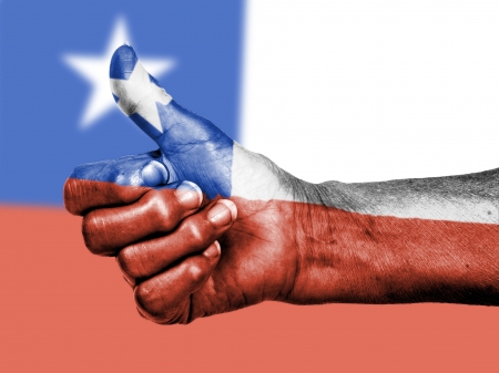 Old woman with arthritis giving the thumbs up sign, wrapped in flag pattern, Chileの写真素材