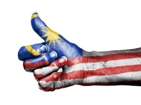 Old woman with arthritis giving the thumbs up sign, wrapped in flag pattern, Malaysiaの写真素材
