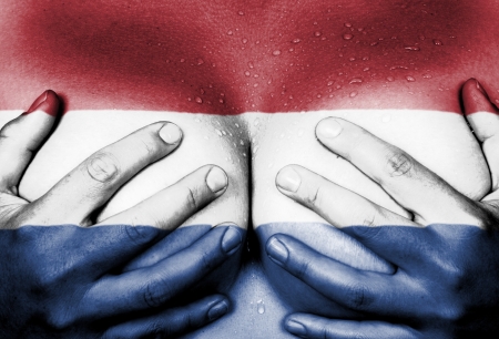 Sweaty upper part of female body, hands covering breasts, flag of Hollandの写真素材