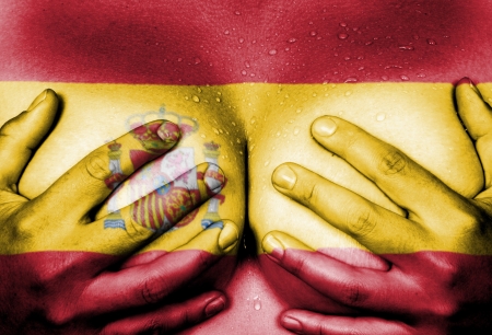 Sweaty upper part of female body, hands covering breasts, flag of Spainの写真素材