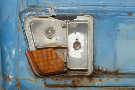 Close-up of busted taillight on rear end of old abandoned and rusted carの写真素材