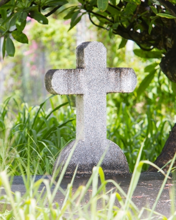 Cross on tombstone under a green treeの写真素材