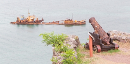 Very old rusted canon pointing at a sunken ship, concept of humorの写真素材