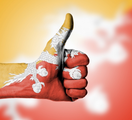 Closeup of male hand showing thumbs up sign, flag of Bhutanの写真素材