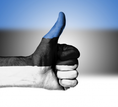 Closeup of male hand showing thumbs up sign, flag of Estoniaの写真素材