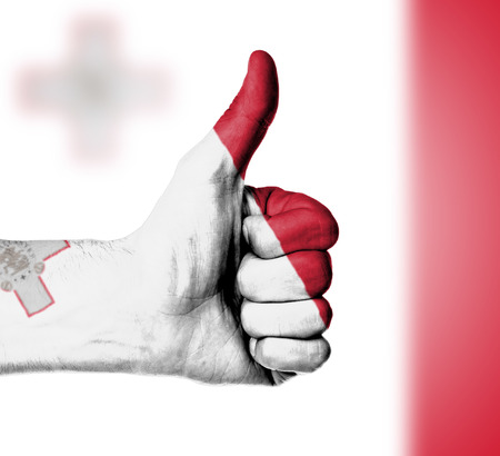 Closeup of male hand showing thumbs up sign, flag of Maltaの写真素材