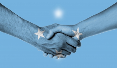Man and woman shaking hands, wrapped in flag pattern, Micronesia