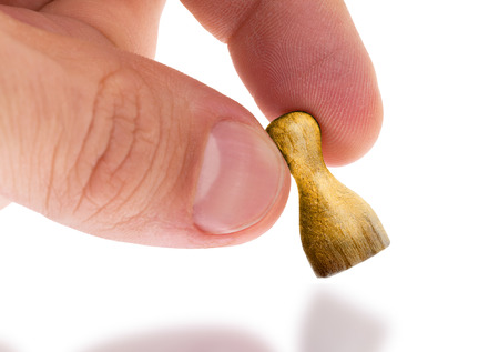 Hand holding wooden pawn with a painting, selective focus, goldの写真素材