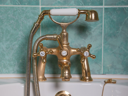 Vintage bath taps, golden tap with a green wallの写真素材