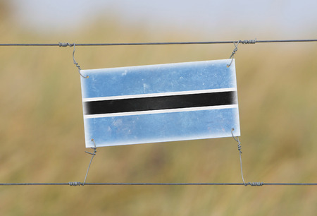 Border fence - Old plastic sign with a flag - Botswanaの写真素材