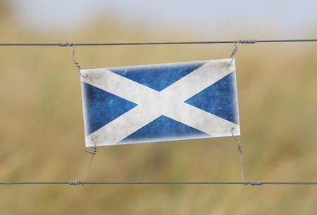 Border fence - Old plastic sign with a flag - Scotlandの写真素材