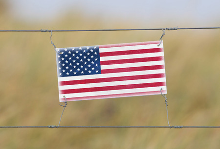Border fence - Old plastic sign with a flag - USAの写真素材