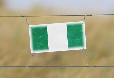 Border fence - Old plastic sign with a flag - Nigeria