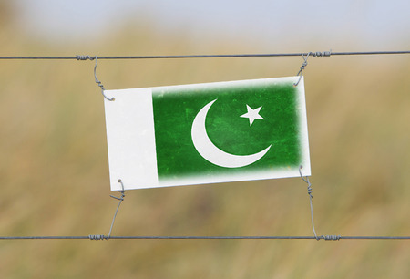 Border fence - Old plastic sign with a flag - Pakistanの写真素材
