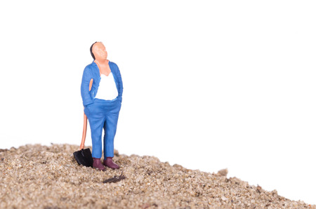 Miniature worker with a shovel on a mountain of sandの写真素材