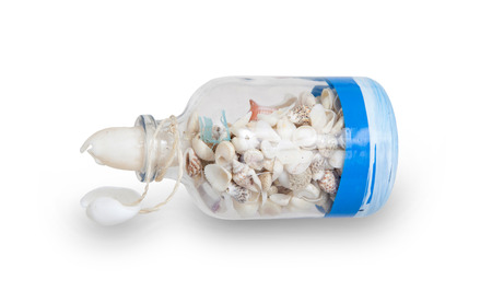 Glass bottle filled with sea shells, isolated on whiteの写真素材