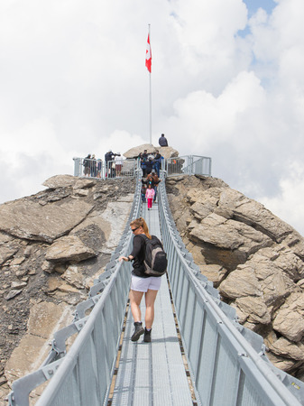 LES DIABLERETS, SWIZTERLAND - JULY 22: People walk at the Glacier 3000 on July 22, 2015. The area houses the world only suspension bridge between 2 mountain peaks.のeditorial素材