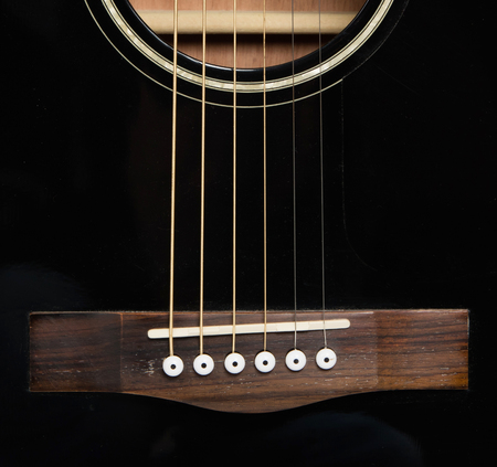 Detail of an acoustic black guitar with the strings and the sound hole