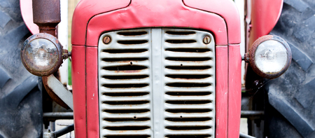 Old tractor face, red, rusty an dentedの写真素材