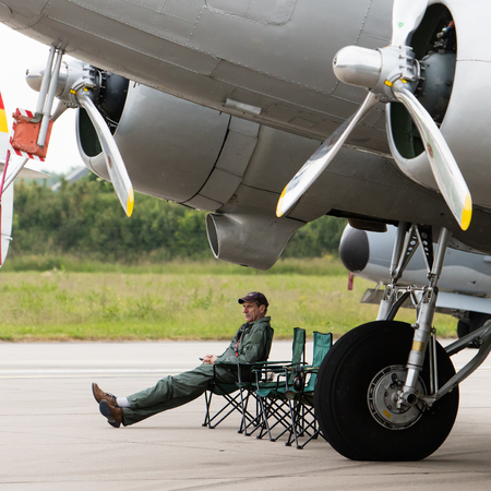 LEEUWARDEN, THE NETHERLANDS - JUNE 11, 2016: Pilot sitting under an old airplane during the open...