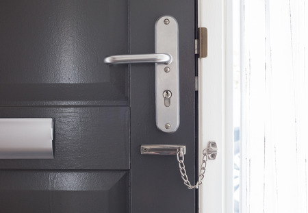 Door chain on a grey door, security measures