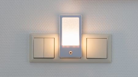 Plastic nightlight illuminating the wall and light switch