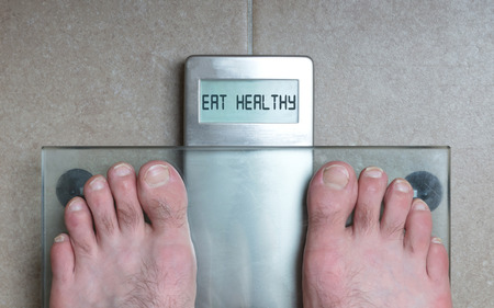 Closeup of man's feet on weight scale - Eat healthyの写真素材