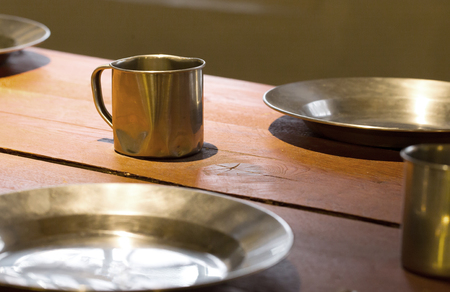 Very old metal cups and plates on a wooden table, old prison