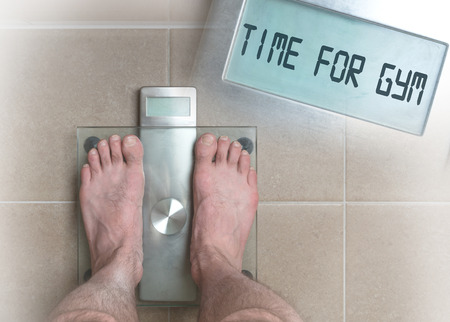 Closeup of man's feet on weight scale - Time for gymの写真素材