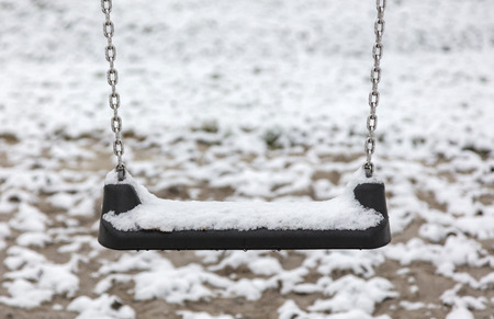 Empty swing in playground - Covered in snowの写真素材