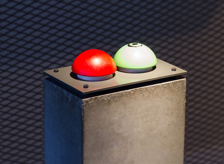 Red and green button on a concrete pillar
