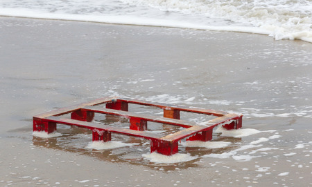 Red palette on a beach, litter on the beachの写真素材