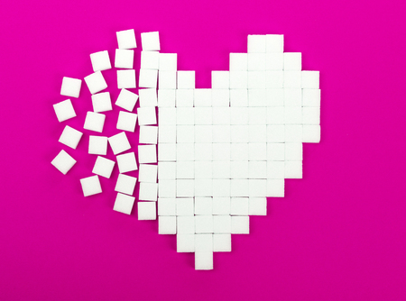 Broken heart made of sugar cubes lies on a trendy pink backgroundの写真素材