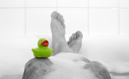 Men's feet in a bright white bathtub, selective focus on toes