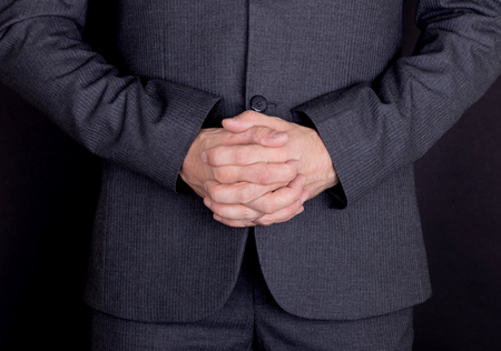 Hands crossed in prayer, man in grey suit