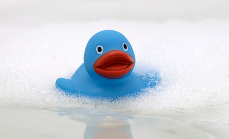 Blue duck in a bathtub, surrounded by soapの写真素材