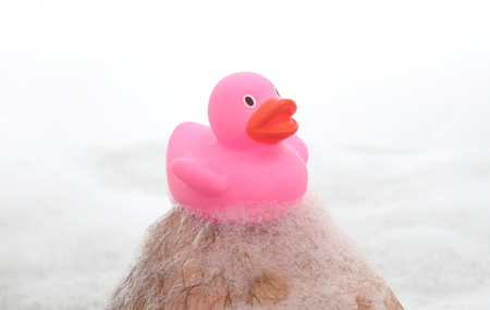 Men's feet in a bright white bathtub, selective focus on toesの写真素材