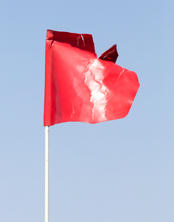 Plastic red flag, isolated on a blue sky