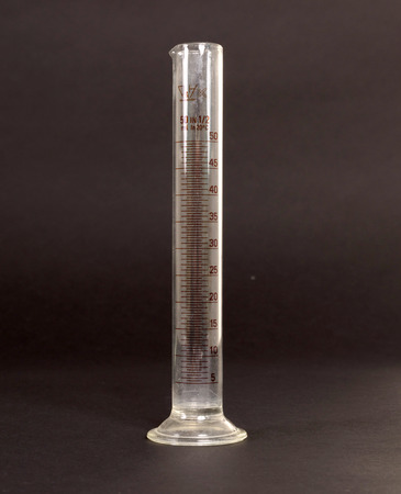 Old measuring cylinder, isolated on black, selective focus