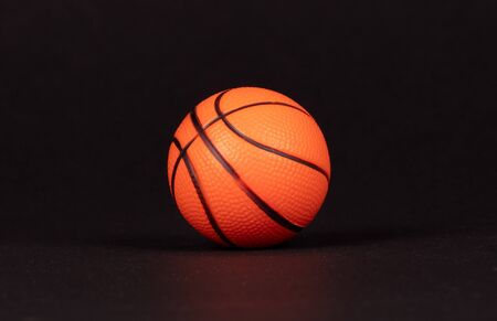 Single small rubber toy in form of basketball, isolated on black backgroundの写真素材